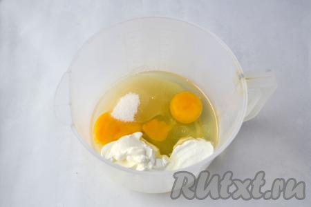 В достаточно объёмную ёмкость разбейте яйца, выложите сметану, всыпьте 100 грамм сахара и влейте 2,5 столовых ложки растительного масла.