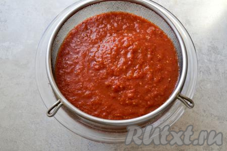 Чтобы избавить кетчуп от семян и шкурок, протрите томатное пюре через сито. Семечки и шкурки, которые останутся в сите, выбросите.
