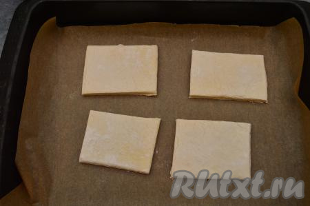 Разрезать разморозившееся слоёное тесто на 4 квадрата (раскатывать тесто не нужно). Выложить квадраты на небольшом расстоянии друг от друга на противень, застеленный пергаментной бумагой.