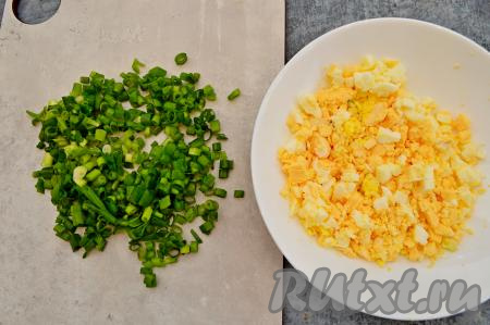 Остывшие варёные яйца очистите. 4 яйца разделите на белки и желтки. Отложите 4 белка для украшения салата. 4 желтка и оставшееся яйцо нарежьте на мелкие кубики. Мелко нарежьте зелёный лук.