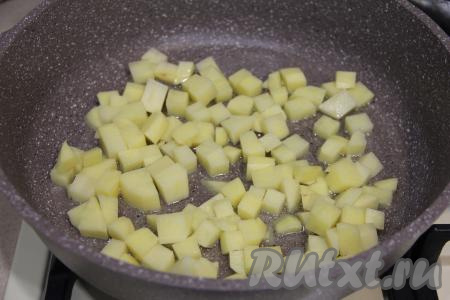 Для начала приготовим начинку, для этого в сковороду нужно влить растительное масло, разогреть его и выложить картошку. Обжарить кусочки картофеля в течение 5 минут, периодически переворачивая, на среднем огне.