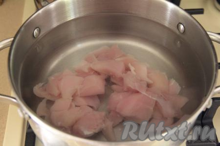 Куриное филе, нарезанное на кусочки (или порционные части курицы), выложить в кастрюлю. Залить мясо 2 литрами воды и поставить на огонь. После закипания куриного бульона тщательно снять пенку. Варить куриное мясо на небольшом огне 25-30 минут. По прошествии времени, если вы брали кусочки курицы на кости, нужно будет достать курочку из бульона, дать немного остыть, отделить мясо от костей, нарезать на части, вернуть куриное мясо в бульон, поставить на огонь.