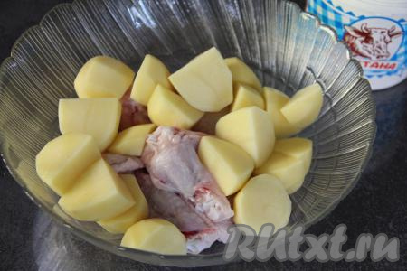 В глубокую миску выложить куриные крылышки и крупно нарезанную картошку. 