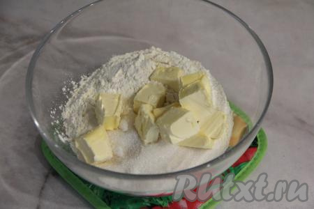 Прежде всего замесим песочное тесто. Для этого нужно в миску всыпать муку и сахар, добавить холодное сливочное масло, нарезанное на кусочки. Масло должно быть из холодильника.