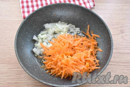 Вливаем на сковороду растительное масло, прогреваем его, а затем выкладываем натёртую на крупной тёрке морковку и мелко нарезанный лук, перемешиваем.