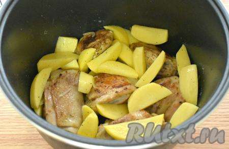 Подготовленные картофельные ломтики выкладываем к обжаренным куриным бёдрам в чашу мультиварки.
