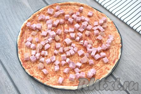 Ветчину (или колбасу) нарезаем на маленькие кубики, распределяем по основе пиццы.