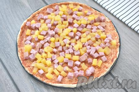 Консервированный ананас тоже нарезаем на маленькие кубики, заполняем ими свободное пространство на основе пиццы.