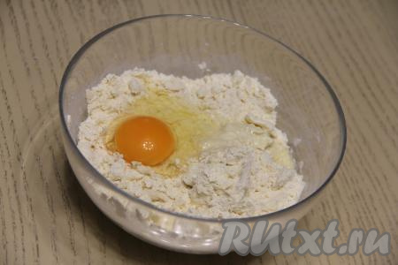 Перетереть масло с мукой в крошку. Добавить сырое яйцо, перемешать тесто сначала ложкой, а затем руками собрать в ком. Величина яйца может быть разной, поэтому если песочное тесто не соберётся в ком, влейте 1 столовую ложку холодной воды, собирая тесто в ком. Если же тесто будет сильно липнущим к рукам, тогда всыпьте совсем немного муки и вмешайте её в тесто.