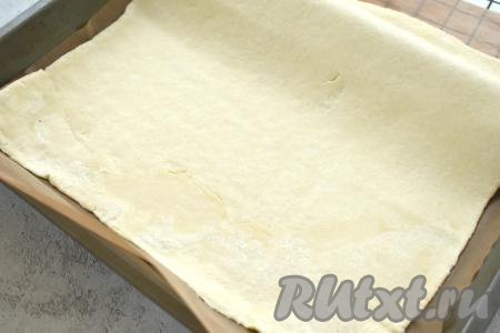 Размороженное тесто на слегка присыпанной мукой поверхности раскатываем в пласт толщиной примерно 2 миллиметра, перекладываем его на противень, заранее застеленный ковриком (или пергаментом) для выпечки.