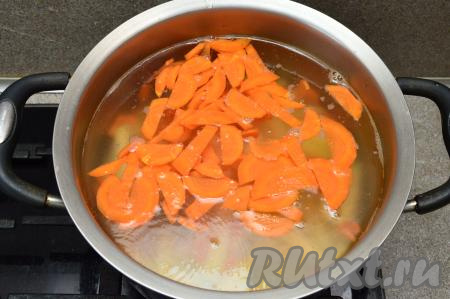 В закипевшую воду выложить морковь и картошку, дать закипеть, уменьшить огонь и варить овощи 15 минут.