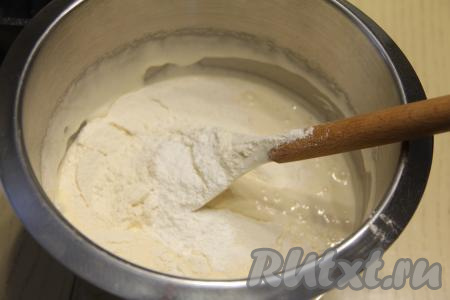 В получившуюся массу всыпать разрыхлитель, соль и половину просеянной муки, перемешать бисквитное тесто лопаткой.