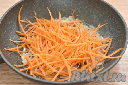 К обжаренному луку выкладываем морковку, натёртую на тёрке для корейской моркови (или нарезанную тонкой соломкой), перемешиваем.