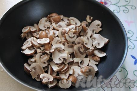 В сковороде разогреть растительное масло, затем выложить шампиньоны, нарезанные на пластинки, обжаривать грибы, периодически помешивая, в течение минут 15 на среднем огне.