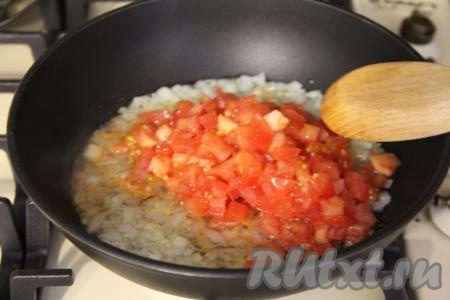 Помидор мелко нарезать и добавить в сковороду к чесноку и луку, перемешать, обжаривать овощи, время от времени помешивая, минут 5.