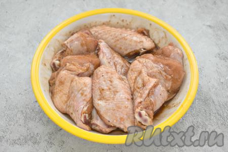 Подготовленные крылья кладём в глубокую миску, вливаем к ним смесь соевого соуса и специй, перемешиваем.