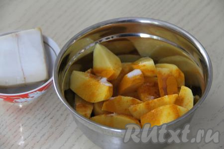 Картошку, нарезанную на крупные дольки, выложить в объёмную миску, добавить специи, соль и растительное масло. Тщательно перемешать, покрывая маслом и специями картофель со всех сторон. 