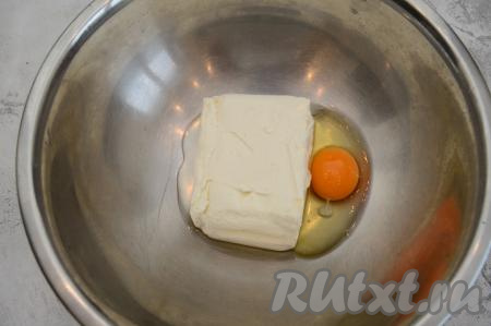 В миску выложить творожную массу и вбить сырое яйцо.