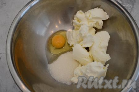 В миску всыпать сахар, вбить сырое яйцо и выложить творожный сыр.