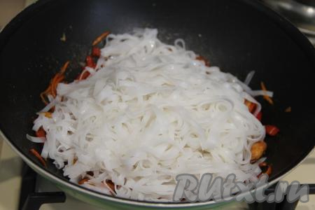 К овощам, обжаренным с креветками в соевом соусе, добавить подготовленную рисовую лапшу.