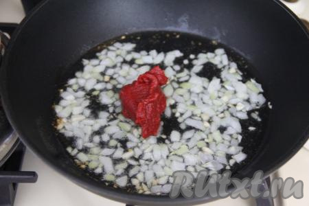 В сковороду с обжаренными луком и чесноком добавить томатную пасту, перемешать и обжаривать 1 минуту.