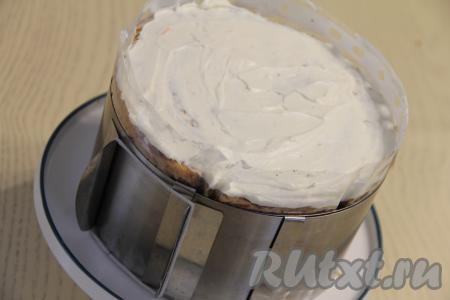 Зажать морковный торт с грецкими орехами в кулинарное кольцо. Частью отложенного крем-чиза смазать верх торта. Отправить тортик в холодильник на ночь. Оставшийся крем поместить в холодильник, он нам понадобится на следующий день для смазывания боков торта.