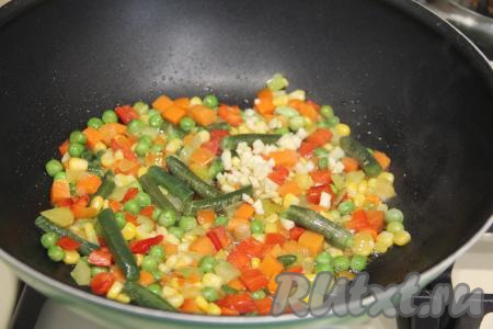 В сковороду добавить мелко нарезанный зубчик чеснока, перемешать и обжаривать овощи 2-3 минуты, иногда помешивая.
