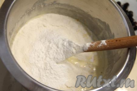 В смесь яиц и кефира всыпать разрыхлитель и половину оставшейся просеянной муки, перемешать тесто для кекса лопаткой до однородности.
