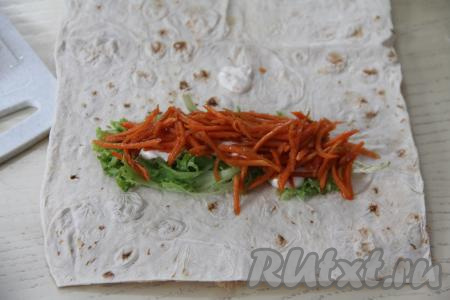 Смазать листья салата 1 столовой ложкой майонеза. Корейскую морковку, если она длинная, нарезать на более короткие полоски. Половину морковки выложить поверх смазанных листьев салата.