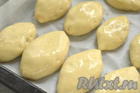 Пирожки с картошкой и луком выкладываем швом вниз на противень, предварительно застеленный пергаментом. Накрываем пирожки полотенцем и оставляем на 20 минут для расстойки теста. Спустя это время смазываем пирожки растительным маслом.