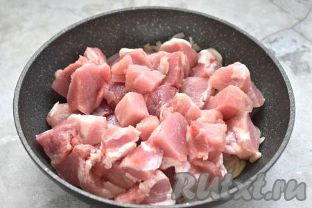 После того как лук станет мягким, добавляем в сковороду кусочки свинины, перемешиваем.