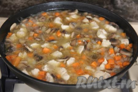 Перемешать рис с овощами, грибами и курицей. Как только вода закипит, убавить огонь до минимума, накрыть сковороду крышкой.