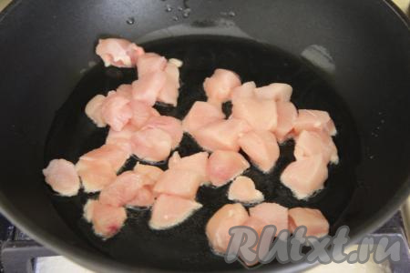 В сковороду влить растительное масло, разогреть, затем выложить куриное филе, нарезанное на небольшие кубики.