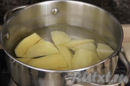 Картошку почистить, нарезать на крупные дольки, выложить в кастрюлю и залить полностью водой. Поставить на огонь и варить картофель с момента закипания 5-7 минут (до полуготовности), затем убрать с огня, воду слить.