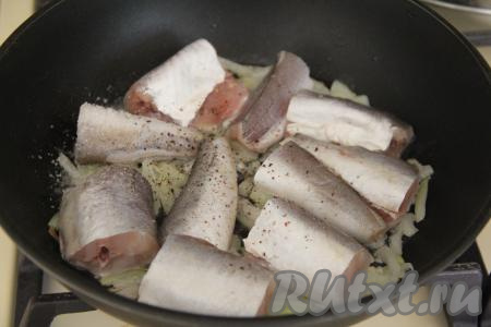 Хека нарезать на порционные кусочки и выложить в сковороду к обжаренному луку. Посолить и поперчить рыбу по вкусу.