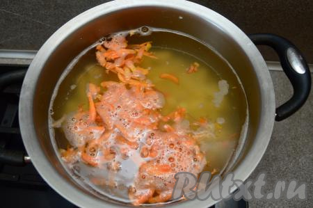 Сразу же добавляем в кастрюлю очищенную и натёртую на крупной тёрке морковку. Доводим воду с рисом и овощами до кипения, варим суп на небольшом огне 15-20 минут (и овощи, и рис должны стать достаточно мягкими, они должны практически полностью свариться).