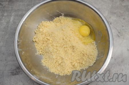Руками перетереть сливочное масло с сухими ингредиентами до получения мелкой, однородной песочной крошки. Вбить в миску с крошкой сырое яйцо.