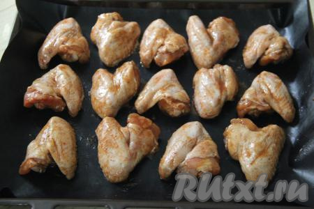 Противень смазать растительным маслом или застелить ковриком (или бумагой) для выпечки. Выложить замаринованные куриные крылья на подготовленный противень.