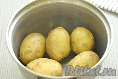 Картошку тщательно моем, не очищая от кожуры, перекладываем в кастрюлю, заливаем полностью водой, ставим на сильный огонь. После закипания, уменьшив огонь, варим картошку до полуготовности (примерно 10-15 минут), затем воду сливаем. Даём картофелю остыть.