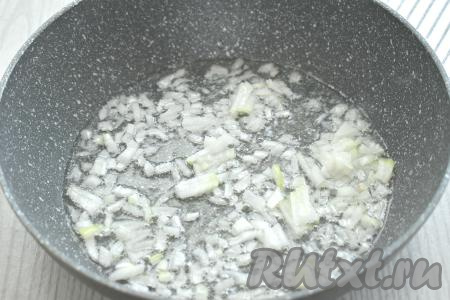 Очищаем лук и морковь. Рис выкладываем в сито, хорошо промываем водой и оставляем на несколько минут, чтобы стекла вода. Разогреваем на сковороде растительное масло, выкладываем луковицу, нарезанную достаточно мелко. Обжариваем лук на среднем огне до прозрачности (минуты 3-4), иногда помешивая. 