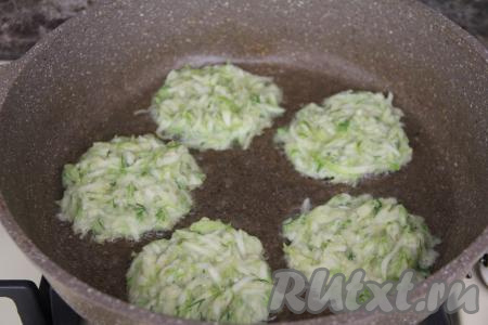 В сковороду влить растительное масло, хорошо разогреть его, уменьшить до среднего огонь, после этого начать выкладывать по 1 столовой ложке кабачкового теста, формируя круглые, плоские оладьи.