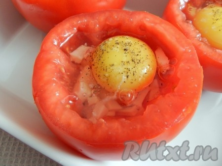 Аккуратно, чтобы не повредить желток, вбить в помидоры яйца, посолить, поперчить. Духовку разогреть до 190 градусов и запекать яичницу в помидоре 20 минут.