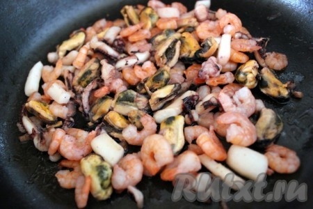 Обжарить морепродукты на оливковом масле в течение примерно трёх минут.