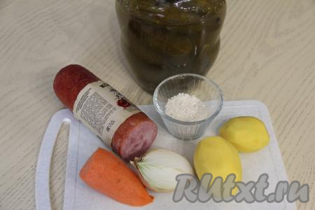 Подготовить продукты для приготовления рассольника с колбасой и рисом. В кастрюлю влить 1,8 литра воды, поставить на сильный огонь. Картошку, лук и морковь почистить. Колбасу можно взять любую (например, варёную, полукопчёную). Можно взять даже несколько видов колбасы (например, варёную куриную колбасу и копчёную колбасу). Рис промыть водой, дать лишней воде стечь.