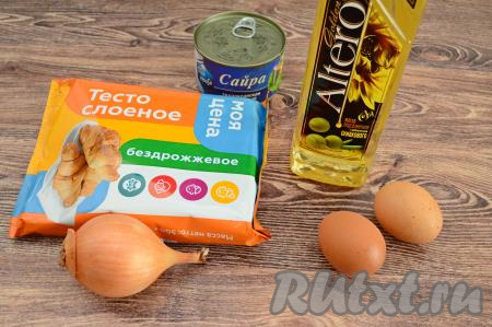 Подготовить продукты для приготовления пирога с сайрой и яйцом из слоёного теста. Для этой выпечки можно взять как дрожжевое слоёное тесто, так и бездрожжевое (я купила бездрожжевое тесто). Разморозить при комнатной температуре слоёное тесто. 1 яйцо нужно заранее отварить в течение 10 минут с момента закипания воды, после этого остудить его и очистить.