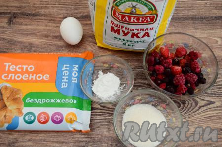 Подготовить продукты. Слоёное тесто можно использовать как дрожжевое, так и бездрожжевое, его нужно достать из морозилки и дать ему разморозиться при комнатной температуре. Замороженные ягоды можно взять любые. Я взяла ассорти из ягод чёрной смородины, клубники и малины. Если на ягодах нет большого количества льда, тогда их можно не размораживать (я не размораживала).