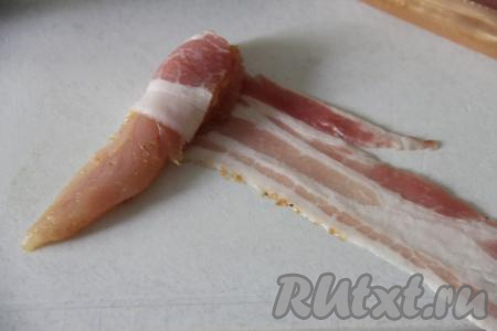 Оставить кусочки куриного мяса промариноваться минимум на 1 час в прохладном месте (можно оставить и на более длительное время). Затем каждый кусочек куриного филе по спирали обернуть в полоску бекона. 