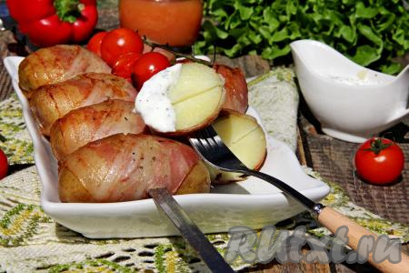 Готовую картошку в беконе переложить с мангала на тарелку для подачи, убрать шампуры. Подать к столу в горячем виде, дополнив любимым соусом. 