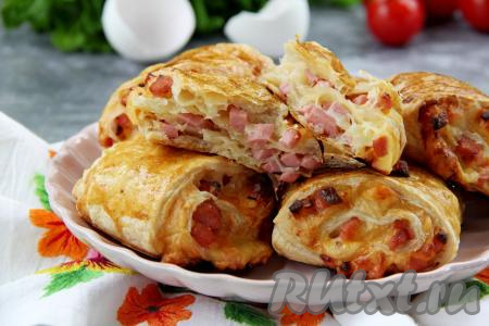 Аппетитные, воздушные булочки из слоёного теста с сытной, нежной начинкой из колбасы и сыра к столу можно подавать и тёплыми, и полностью остывшими. Сытно, нехлопотно и вкусно, попробуйте!