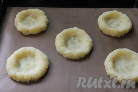 Прижать каждый шарик сверху дном стакана, формируя картофельные гнёзда с бортиком. 